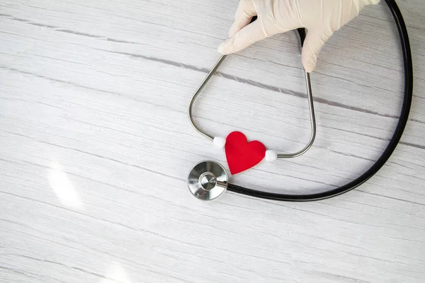Jantung Merah Dan Sarung Tangan Medis Putih Pelindung Memegang Stetoskop — Stok Foto