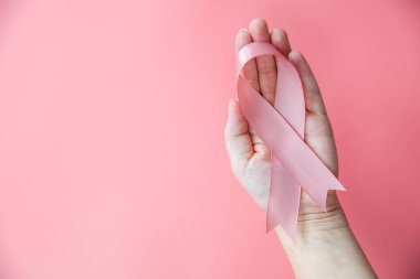 Pembe arka plan üzerinde pembe kurdele tutan kadın eller, göğüs kanseri farkındalığı, kopyalanacak yer, sağlık, metin için kadın kanseri kavramı