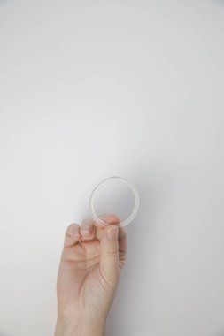 Bir kadının elindeki doğum kontrol yüzüğü beyaz arka planda izole edilmiş, doğum kontrol halkası yakın çekim fotokopi alanı için vajinal halka