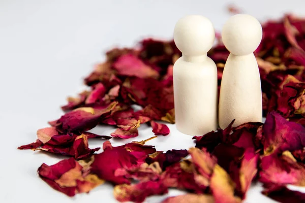 Real love, lover, couple concept. Two wooden figures with red rose petals on white background, standing together isolated on white background. copy space space for text