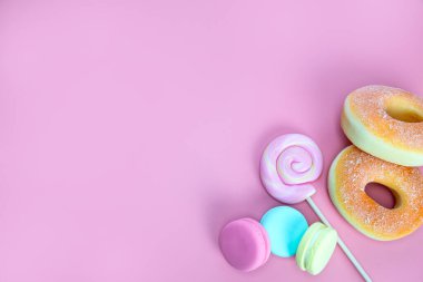 Şeker tatlısı konsepti. Pembe lolipop ve çörekler, pembe arka planda badem kurabiyeleri, metin için üst görünüm boşluğunu kopyala