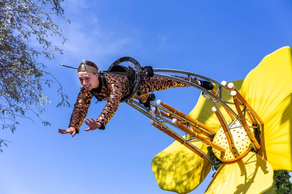 Dubai, BAE, 09.12.2021. 2020 Dubai Daily Parade Fuarı 'nda Arı kostümlü bir kadın büyük sarı çiçeğe akrobasi yapıyordu..