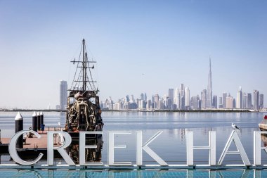 Dubai, BAE, 22.02.2021. Dubai Creek Limanı tabelasında Siyah İnci Korsan Gemisi, Dubai Şehir Merkezi silueti var..