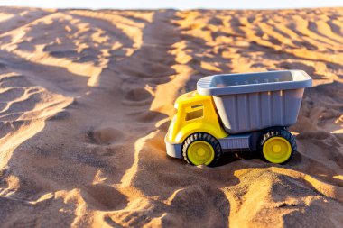 Sarı oyuncak kamyonu çöldeki kumun üzerine boşalttı..