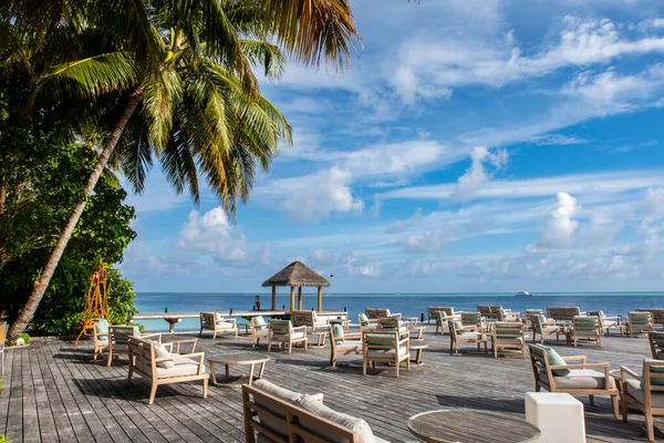 Wooden platform overlooking the ocean with tables and sofas, restaurant in a luxury resort, tropical paradise, Maldives.