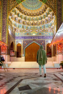 Müslüman bir kadın Dubai 'deki İmam Hüseyin Camii' ne renkli fayans cephesi ve İran mimarisi ile giriyor. Metin çevirisi: Kuran yazıtları.