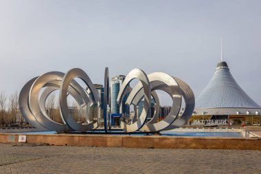 Nur Sultan (Astana), Kazakistan, 11.11.21. Arka planda Khan Shatyr Eğlence Merkezi ile Nur Sultan 'daki Aşıklar Parkı' nda modern heykel ve çeşme.