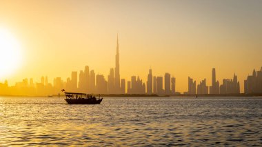 Gün batımında Dubai şehir merkezi silüeti Dubai Creek Kanalı 'ndan geçen bir turist teknesiyle Dubai Creek Limanı gezinti güvertesinden görüldü..