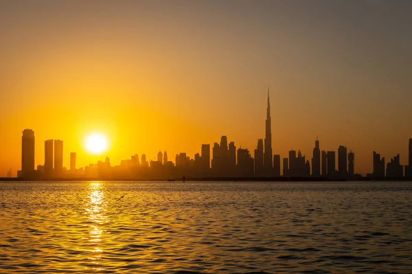 Dubai Şehir Merkezi gün batımında ufuk çizgisi Dubai Creek Limanı gezinti güvertesinden görülüyor.