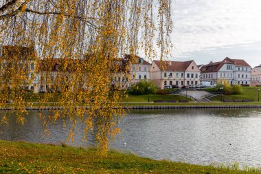 Minsk, Belarus 'taki Trinity Banliyösü, Upper City Minsk' in en eski bölgesinde, sonbaharda Svislach Nehri kıyısında turuncu sonbahar yapraklarıyla eski renkli geleneksel binalar..