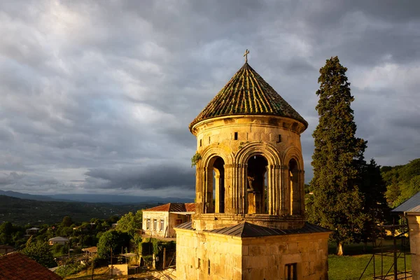 stock image Gelati Monastery belfry (bell tower), medieval monastic complex near Kutaisi, Georgia founded by King David IV, sunset view with dark cloudy ominous sky.