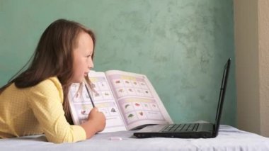 Kız dizüstü bilgisayarla yatakta oturuyor.