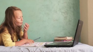 Kız dizüstü bilgisayarla yatakta oturuyor.