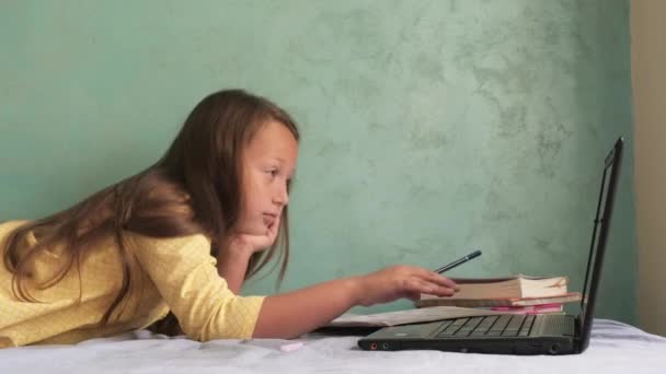 Het meisje zit op het bed met een laptop — Stockvideo