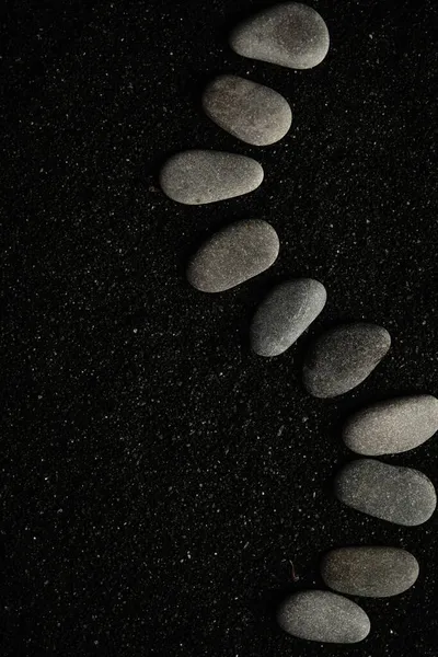 Pequeños guijarros de mar se colocan sobre un fondo negro — Foto de Stock