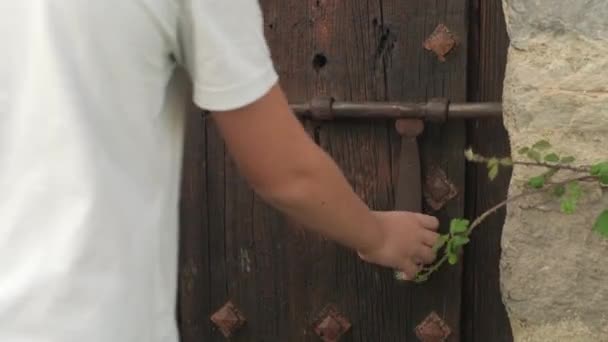 Мальчик открывает деревянную дверь — стоковое видео