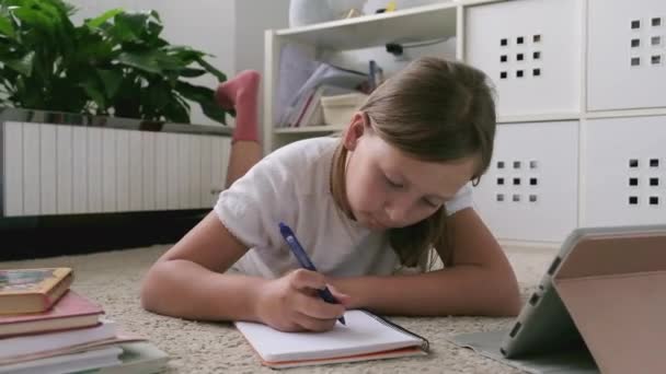 Uma menina com um tablet faz seu dever de casa — Vídeo de Stock