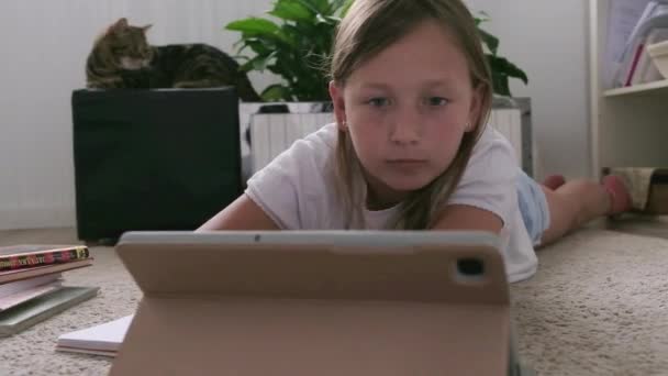 Una chica con una tableta hace su tarea — Vídeo de stock