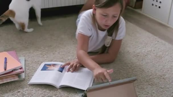 Una chica con una tableta hace su tarea — Vídeo de stock