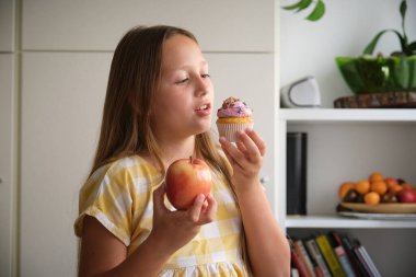 Meyve ya da tatlılığın zor bir seçimi. Kız kek ve elma arasında seçim yapar.
