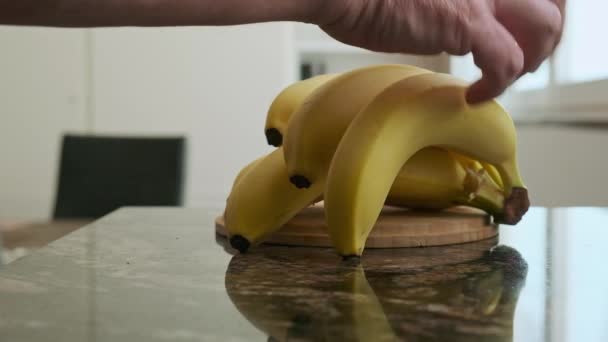 Hombre Toma Plátano Montón Mesa Cocina — Vídeo de stock