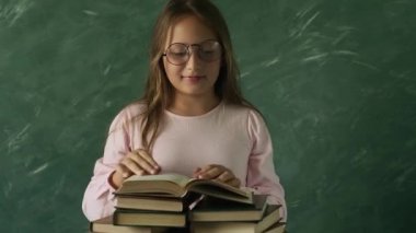 Kitaplarla poz veren gözlüklü güzel küçük kız.