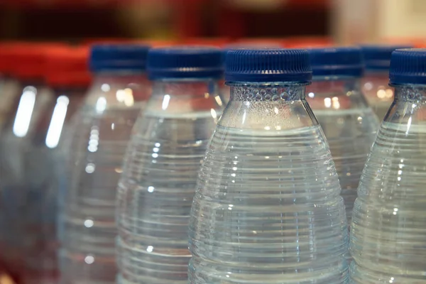 small bottles of drinking water on the shelf in the store close-up