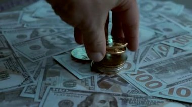 Masada dolar ve bitcoin var, adamın eli bozuk paraları ayırıyor.