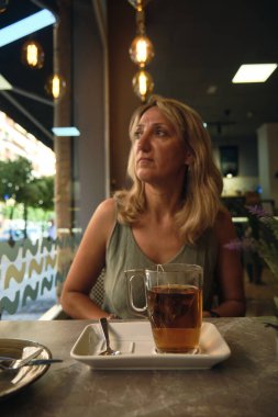 Bir kız zarif bir kafede keklerle bir saat içer.