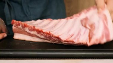 pork ribs are cut on a wooden board by mens hands