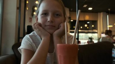 blonde girl in a cafe with a glass of fruit smoothie