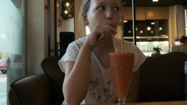 blonde girl in a cafe with a glass of fruit smoothie