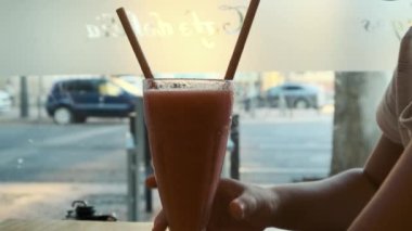 in a cafe, a girl drinks a smoothie
