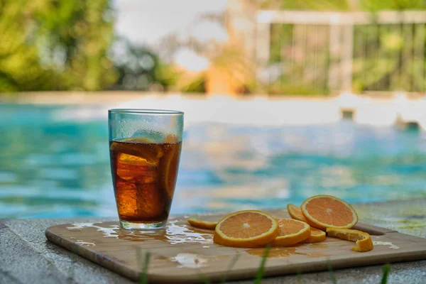 in a glass of cooling drink with sliced citrus fruits near the pool