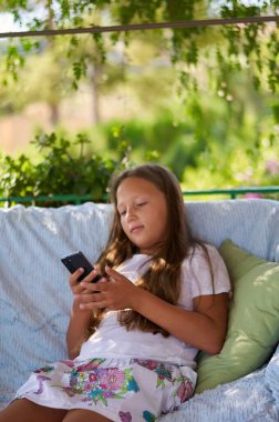 blonde girl sitting on the terrace with a phone