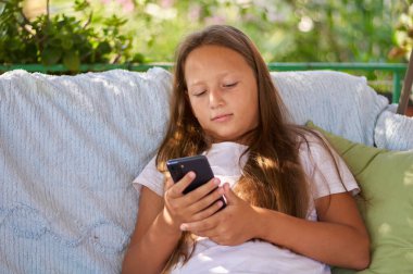 blonde girl sitting on the terrace with a phone