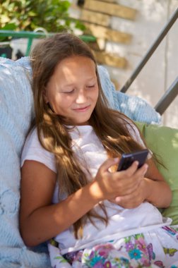 blonde girl sitting on the terrace with a phone