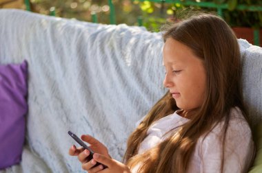 blonde girl sitting on the terrace with a phone