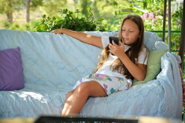 blonde girl sitting on the terrace with a phone