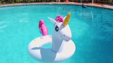a white inflatable circle in the shape of a unicorn floats in the pool