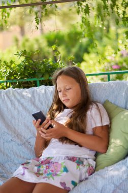 blonde girl sitting on the terrace with a phone
