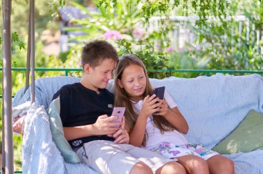 boys and a girl are sitting on the terrace with phones and playing