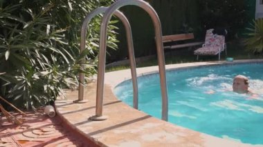 blonde girl comes out of the pool and wipes herself with a towel