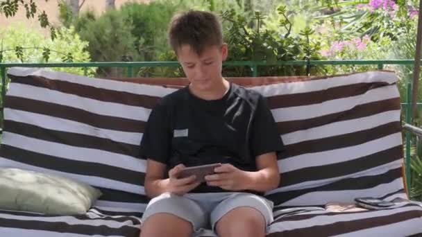 在阳台上 一个青少年在一个小玩意上玩游戏 — 图库视频影像