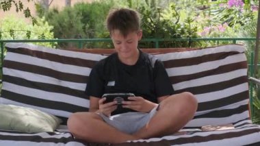Terasta, bir genç bir aletin üzerinde oyun oynuyor.