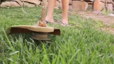 Bahçesinde elektrikli çim biçme makinesi olan bir çocuk çimleri biçiyor.