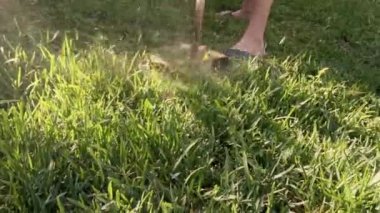 Bahçesinde elektrikli çim biçme makinesi olan bir çocuk çimleri biçiyor.