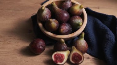 Yanlarındaki ahşap kasede olgun incirler bir bütün ve parçalara bölünmüş.