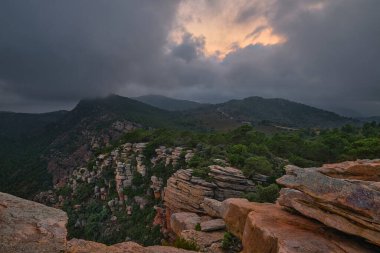 Gökyüzü bulutlarla kaplıdır. Dağların arka planında parlak bir nokta vardır.