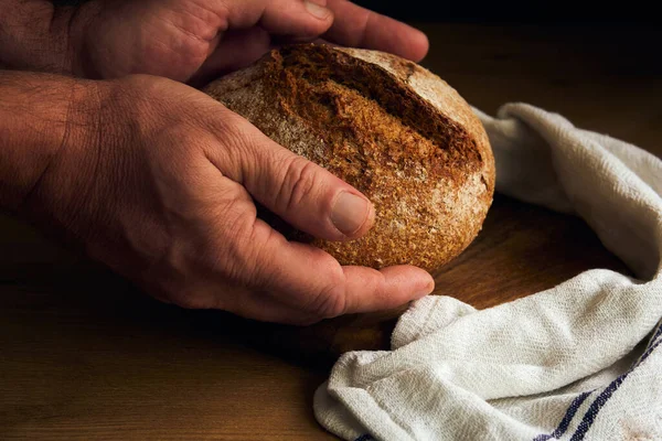 black round bread in the hands of a man in the style of rustic